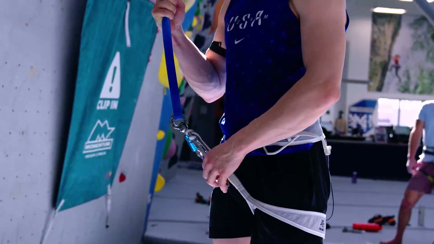 A speed climber clipping into the auto belay before a run