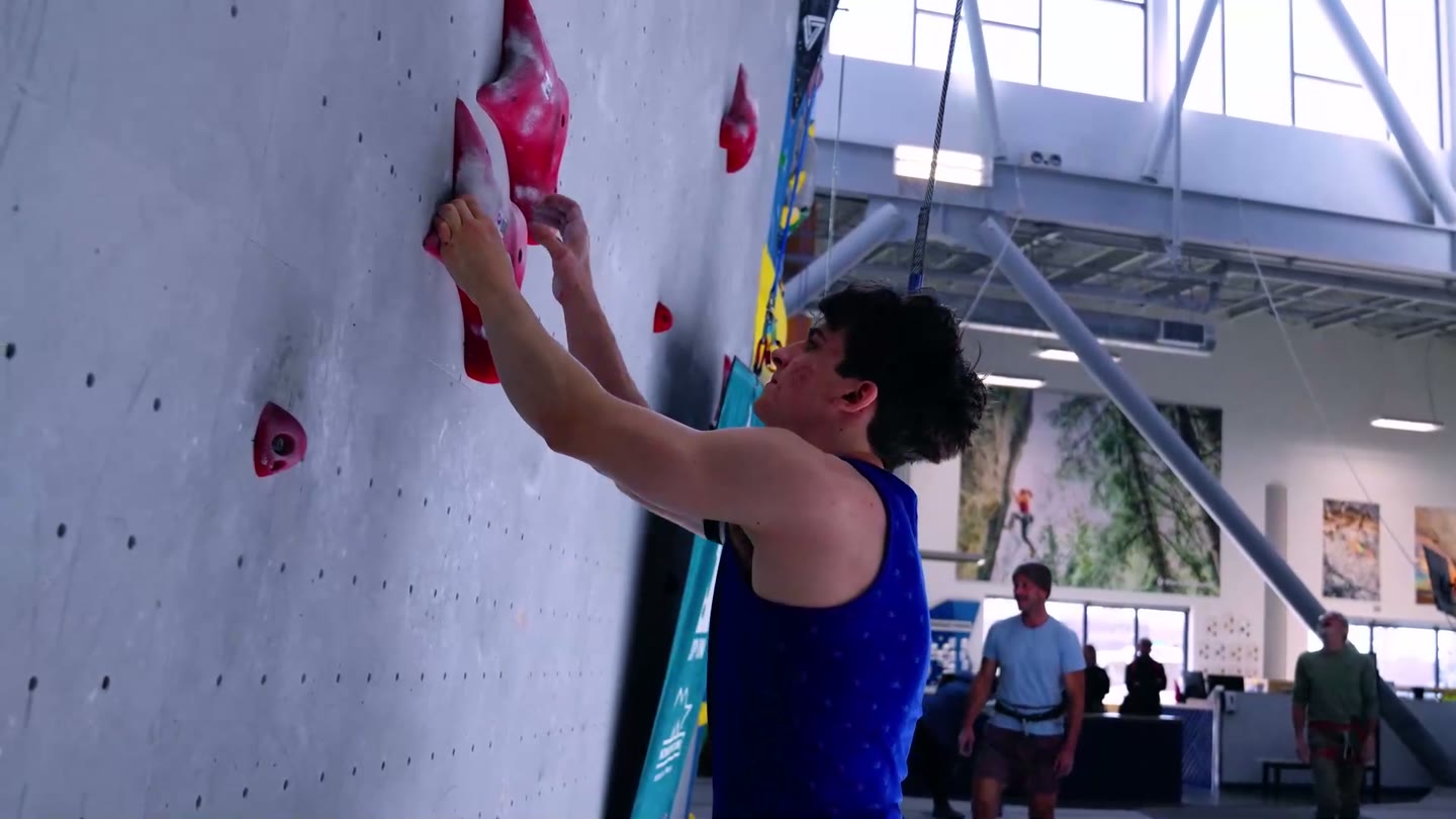 A speed climber reaching for a hold mid-run
