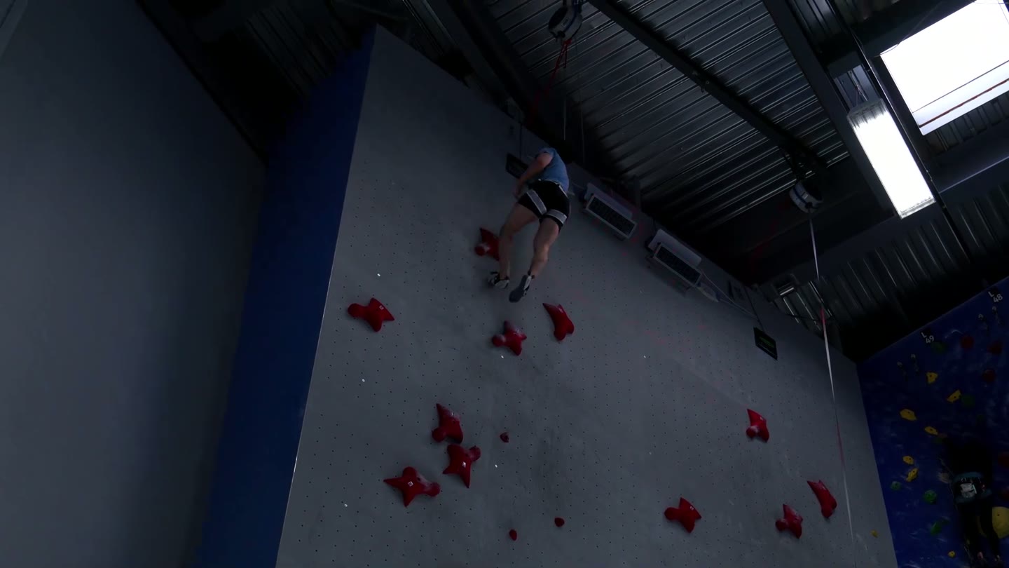 A speed climber high on a competition speed wall
